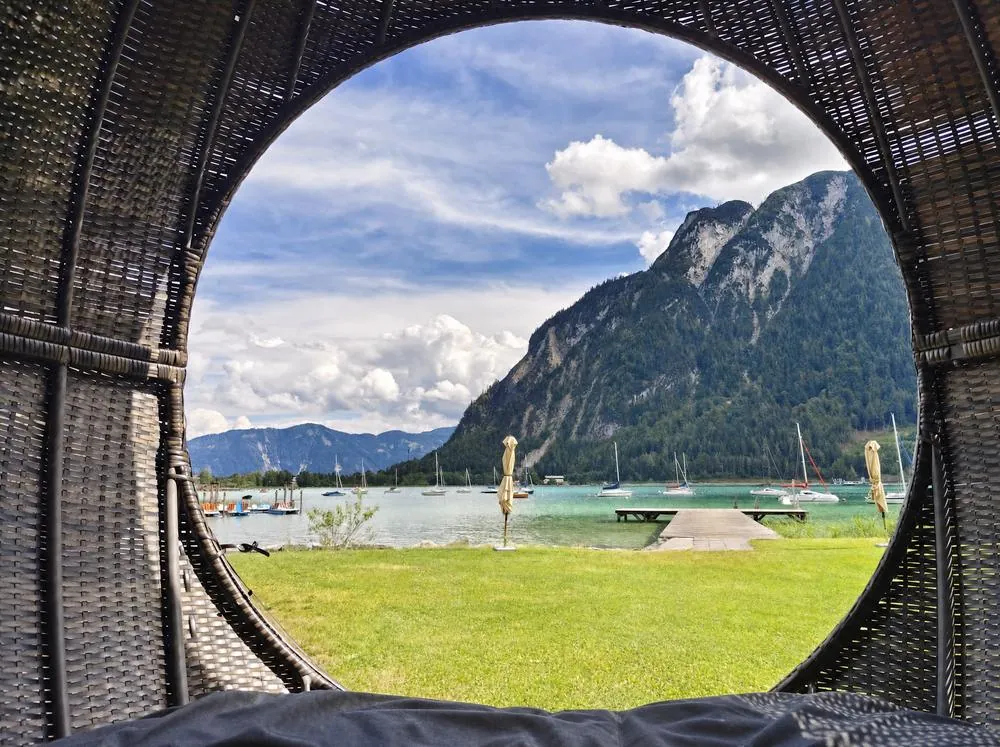 Blick aus einer Rattan-Relax-Kugel über die Seewiese auf den Achensee