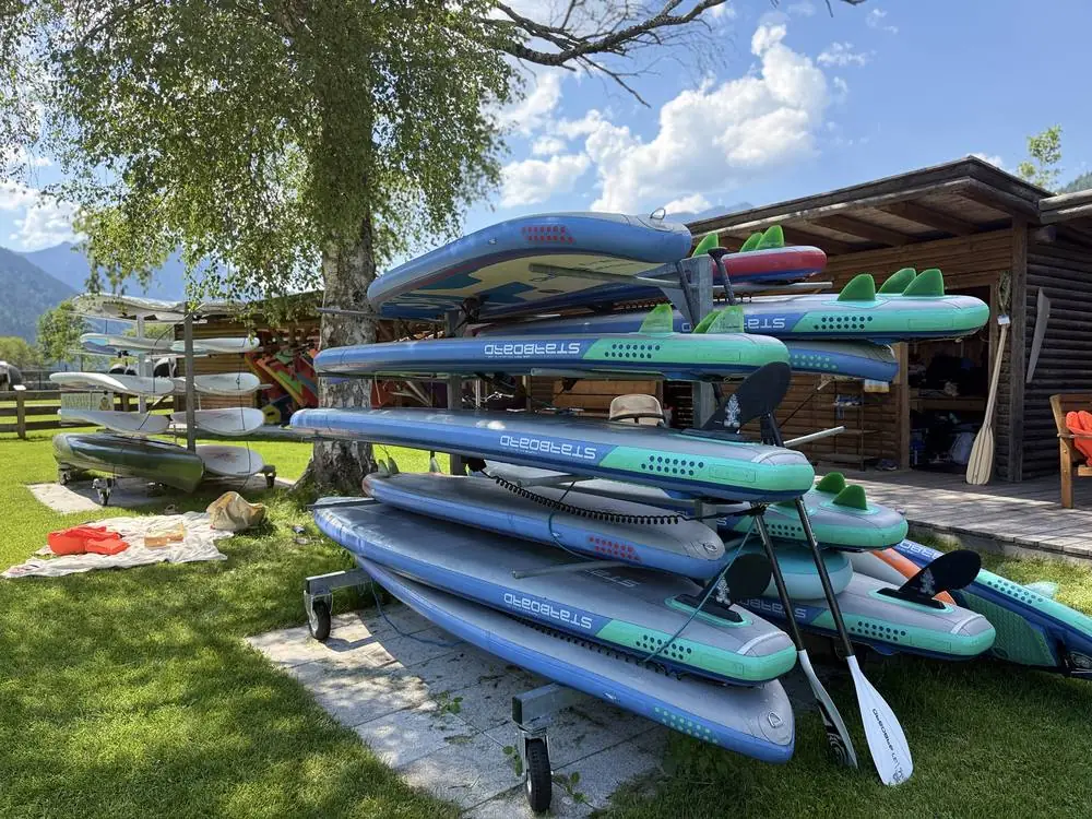 SUP-Verleih am Achensee: gestapelte Starboard-Boards mit Paddeln vor der Hütte