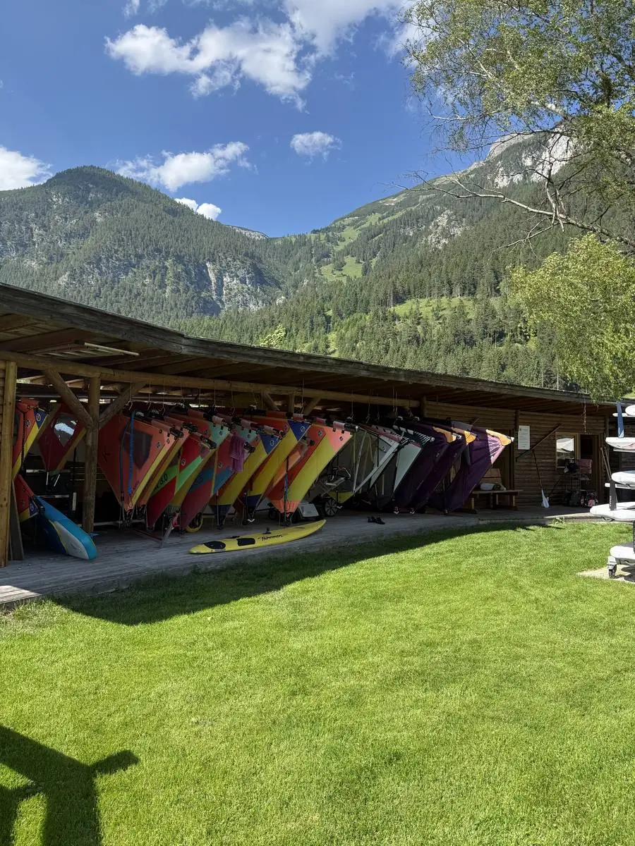 Windsurf-Verleih am Achensee: Reihe aufgeriggter Segel in allen Größen